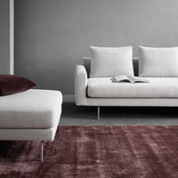 Modern grey sofa with white cushions and a deep burgundy rug, creating a chic, contemporary living space.