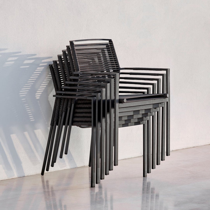 Stacked black chairs featuring sleek lines and modern design, casting layered shadows on a light surface.