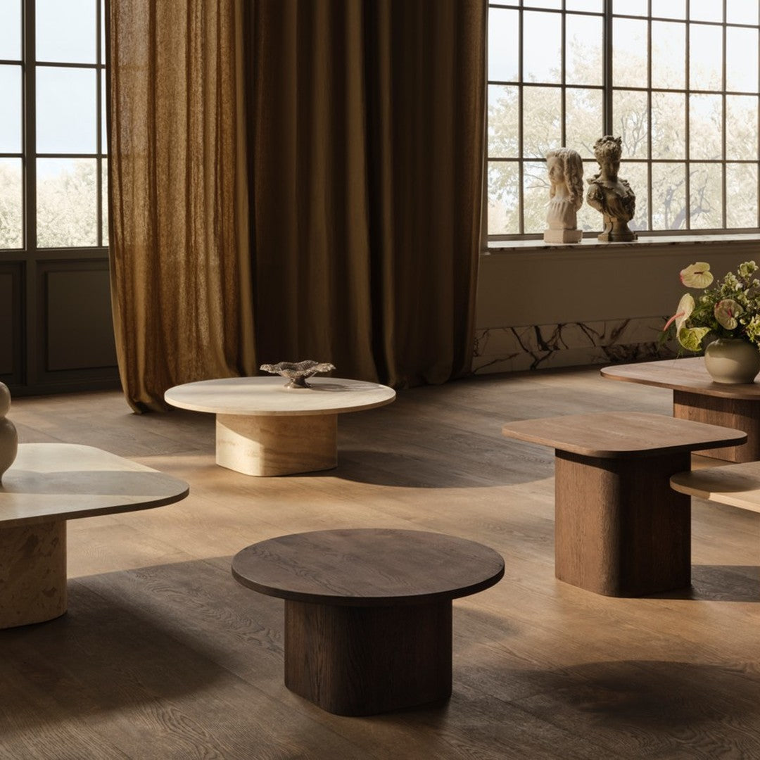 "Modern coffee tables in neutral tones of beige, cream, and brown with sleek, minimalist designs on a warm wooden floor."