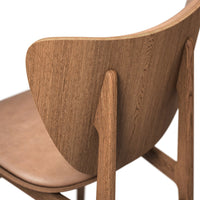"Warm wood tone chair with smooth curves and natural grain, featuring a minimalist design and soft leather seat."