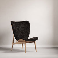 "Elegant black textured chair with a curved silhouette and natural wood legs, ideal for modern interiors."