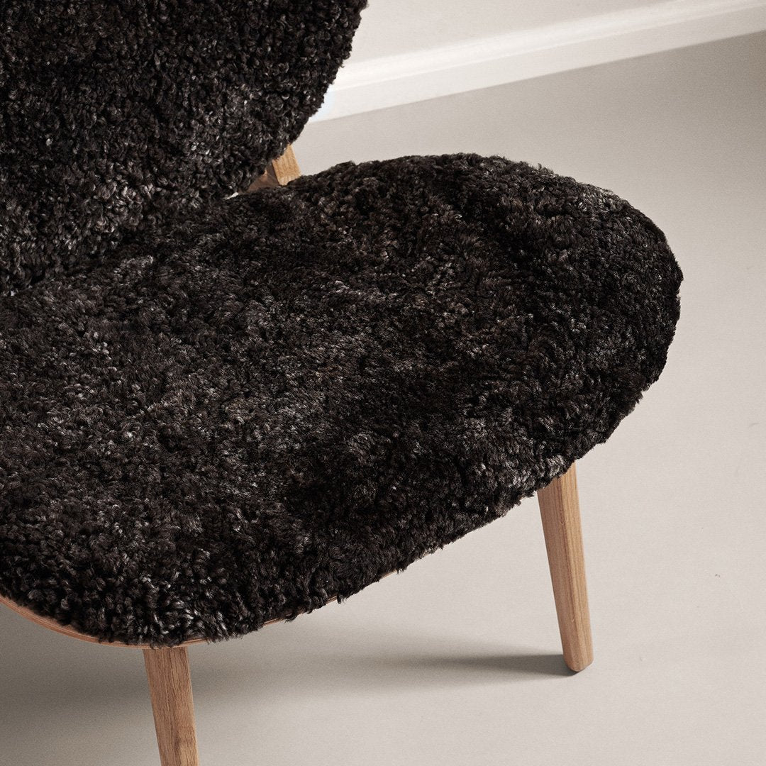 Black textured chair cushion with a plush, shaggy pattern on wooden legs, creating a cozy, modern look.