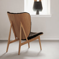 Mid-century modern chair featuring natural wood tones and a textured black seat, set against a minimalist backdrop.