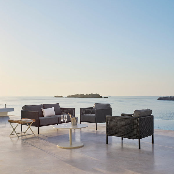 Modern outdoor seating set in deep gray with sleek lines, paired with a minimalist white side table.