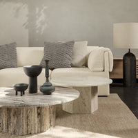 Neutral-toned living room with a light beige sofa, textured gray pillows, and natural wood accent tables.