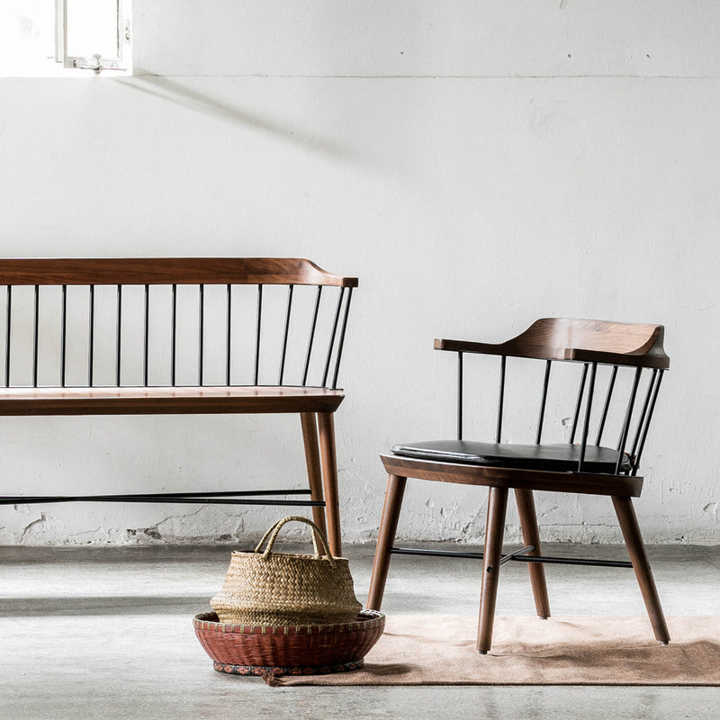 "Mid-century wood and black metal furniture with natural textures and neutral tones, featuring a woven basket accent."