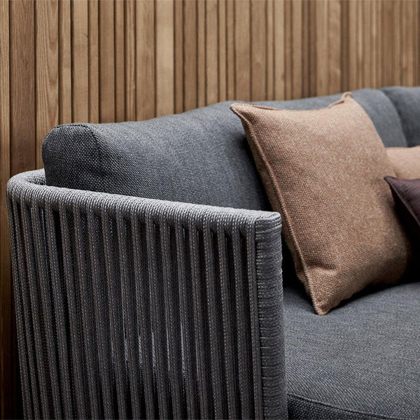 Gray striped sofa with contrasting brown and darker pillows against a wooden backdrop. Modern and stylish design.