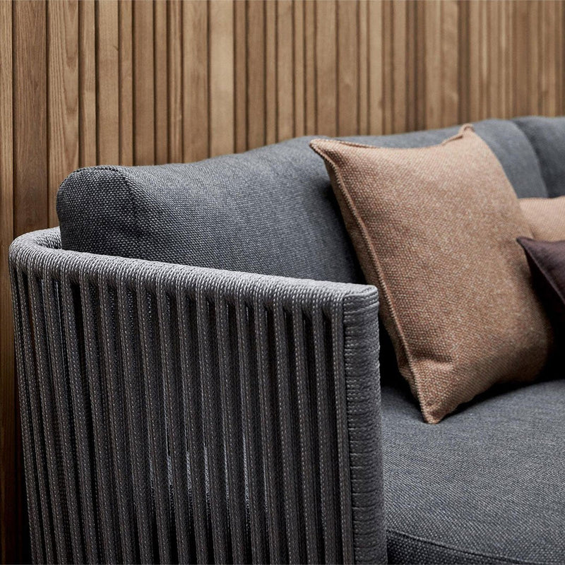 Gray striped sofa with contrasting brown and darker pillows against a wooden backdrop. Modern and stylish design.