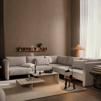 Light gray sectional sofa in a minimalist living room with earthy tones and soft textures.