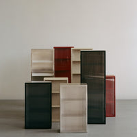 "Stacked cabinets in black, beige, red, and translucent finishes with vertical ribbed patterns."