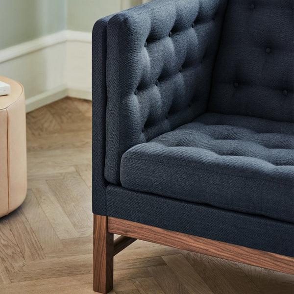 Dark blue tufted upholstery on a sleek wooden frame, featuring a textured pattern against a light wooden floor.