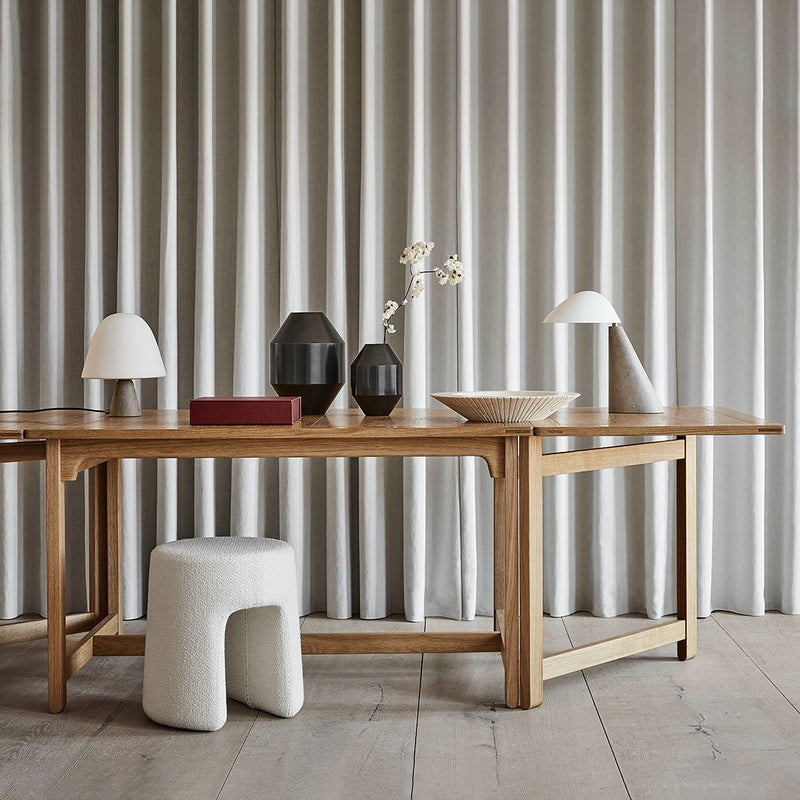 Natural wood table with beige and white decor items, featuring soft gray curtains in the background. Minimalist and modern design.