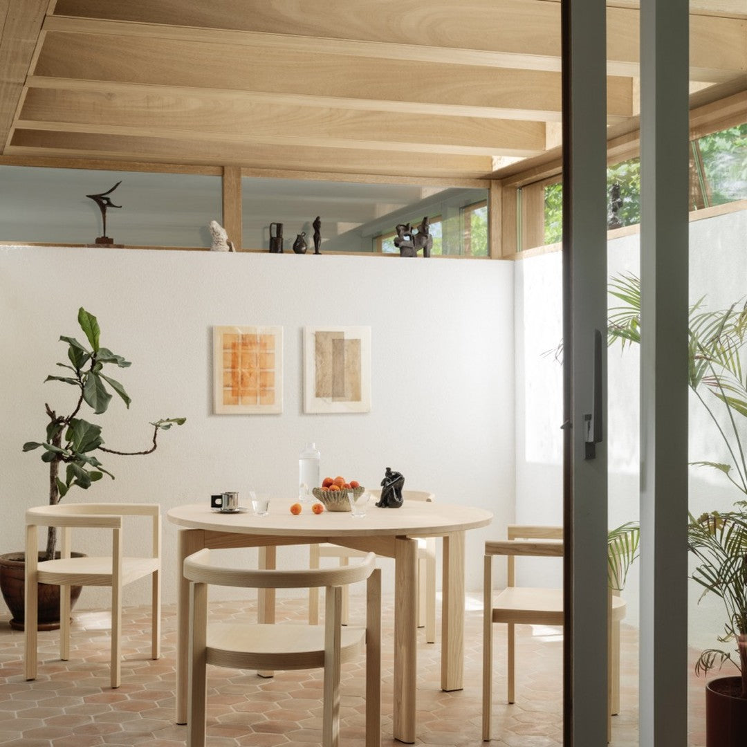 Light wood furniture, earthy orange and beige patterns on walls, with green plants highlighting an airy, modern space.