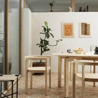 Natural wood tones, earthy terracotta floor, green plant accents, and warm beige wall colors create a serene dining space.