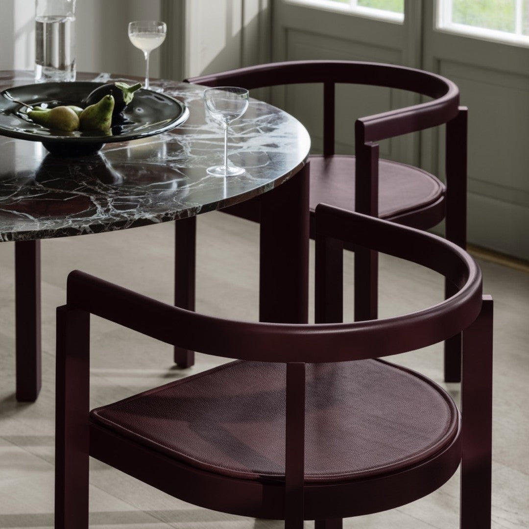 Burgundy curved chairs with textured seats paired with a sophisticated black and white marble table. Elegant design accents.
