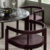 Burgundy curved chairs with textured seats paired with a sophisticated black and white marble table. Elegant design accents.