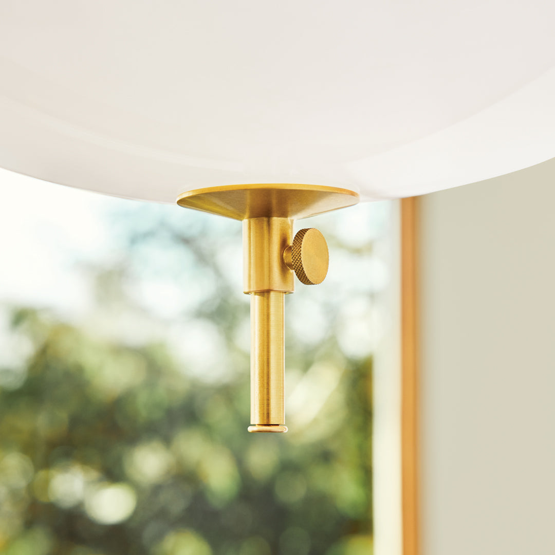 Gold metal pendant lamp holder with a sleek, minimalist design, featuring a white globe and natural light backdrop.