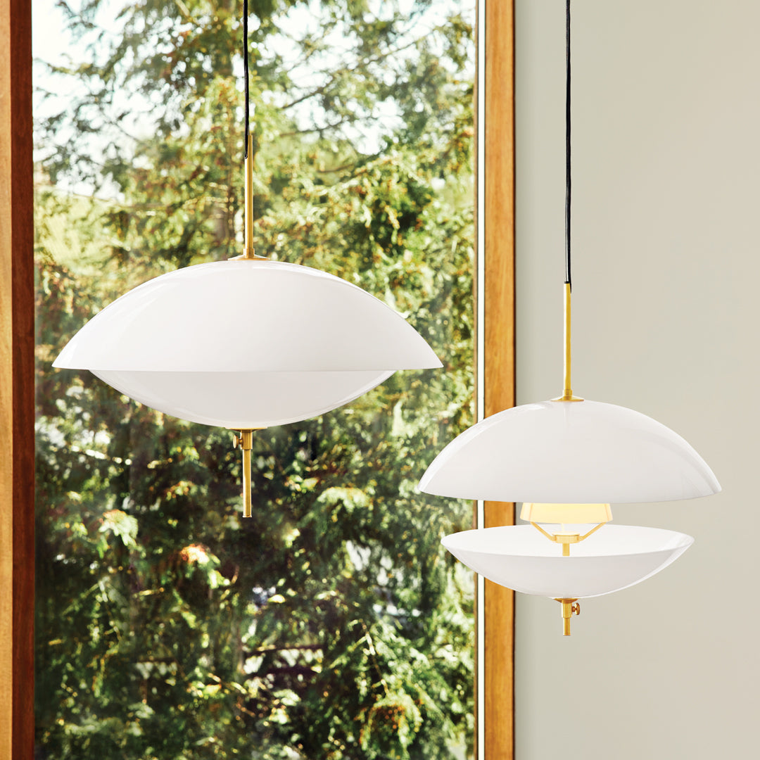 Two elegant white pendant lights with smooth, curved shapes and gold accents, set against a natural backdrop.