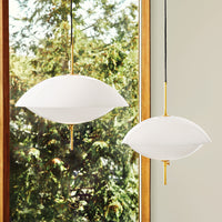 Pair of modern white hanging lamps with rounded shapes and brass accents, set against a natural outdoor backdrop.
