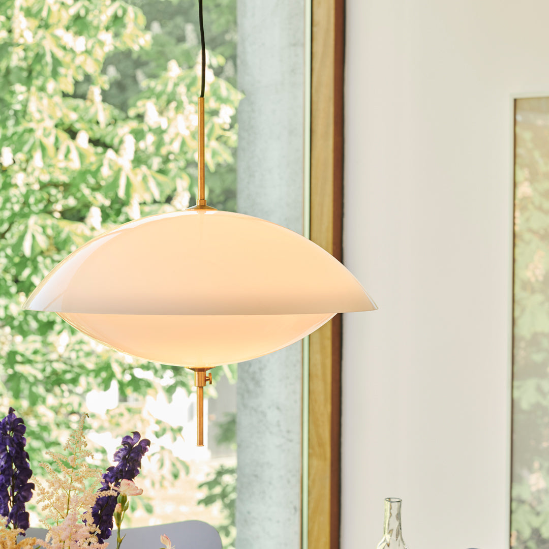 "Soft white lamp with a smooth oval shape, complemented by subtle brass accents and a minimalist design."