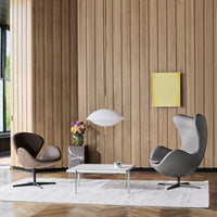 Elegant grey and brown armchairs with a modern white pendant light, set against a warm wooden wall.