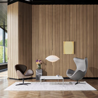 Contemporary lounge featuring brown and gray chairs, warm wood panels, and a soft white rug, creating an inviting atmosphere.