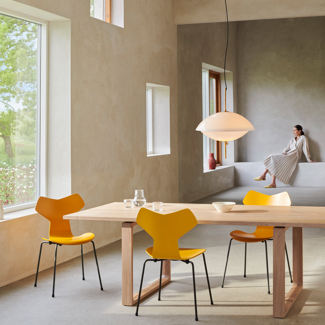 Yellow dining chairs around a wooden table in a soft, neutral-toned room with natural light and minimalistic decor.