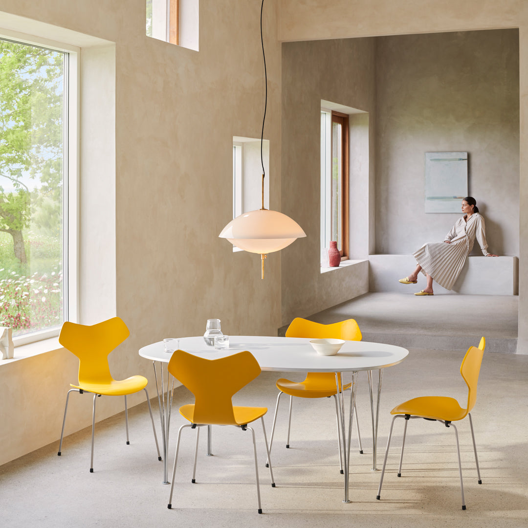 Bright yellow chairs surround a sleek white table in a soft, neutral-toned room with natural light.