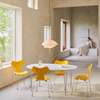 Bright yellow chairs surround a sleek white table in a soft, neutral-toned room with natural light.