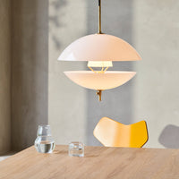 "Modern pendant lamp in soft white and gold, featuring smooth, curved layers against a neutral backdrop."