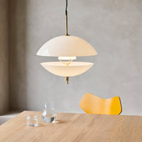Modern white glass pendant lamp with brass accents, featuring a sleek, minimalist design and smooth surfaces.