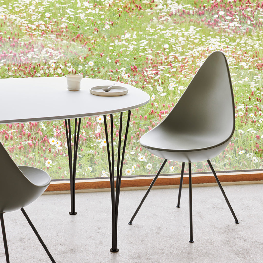 Minimalist gray dining chair and table with sleek black legs, set against a vibrant floral background.