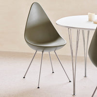 Olive green teardrop chair with sleek chrome legs, set against a neutral background and minimalist white table.