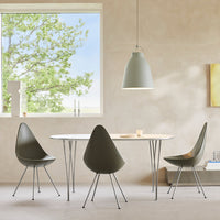 Modern dining table with a smooth white surface, complemented by olive green chairs and a soft gray pendant light.