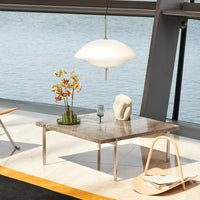 Marble tabletop with gray and beige tones, accented by a sleek white pendant lamp and vibrant floral arrangements.