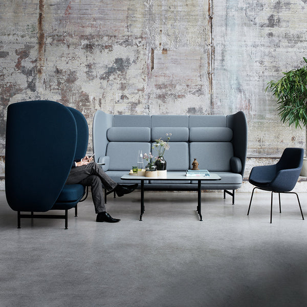 Modern gray and blue sofa set with sleek lines against a rustic backdrop, featuring patterned upholstery and minimalist design.