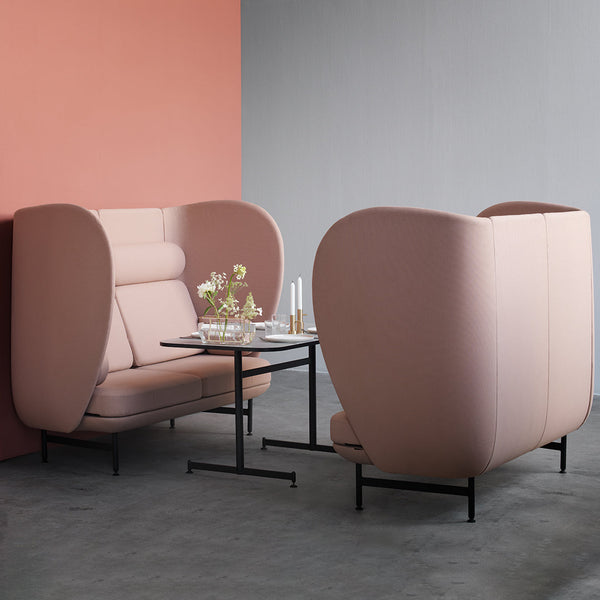 Soft pink upholstered seating with a sleek black table, set against a gray and coral backdrop for a modern aesthetic.