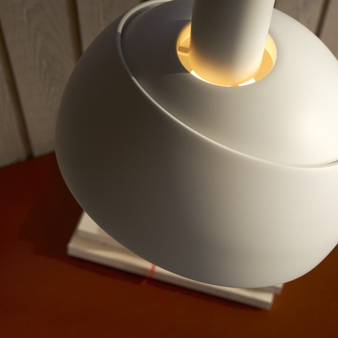 Close-up of a white lamp with a gold base on a wooden surface.