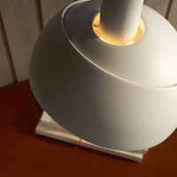 Close-up of a white lamp with a gold base on a wooden surface.