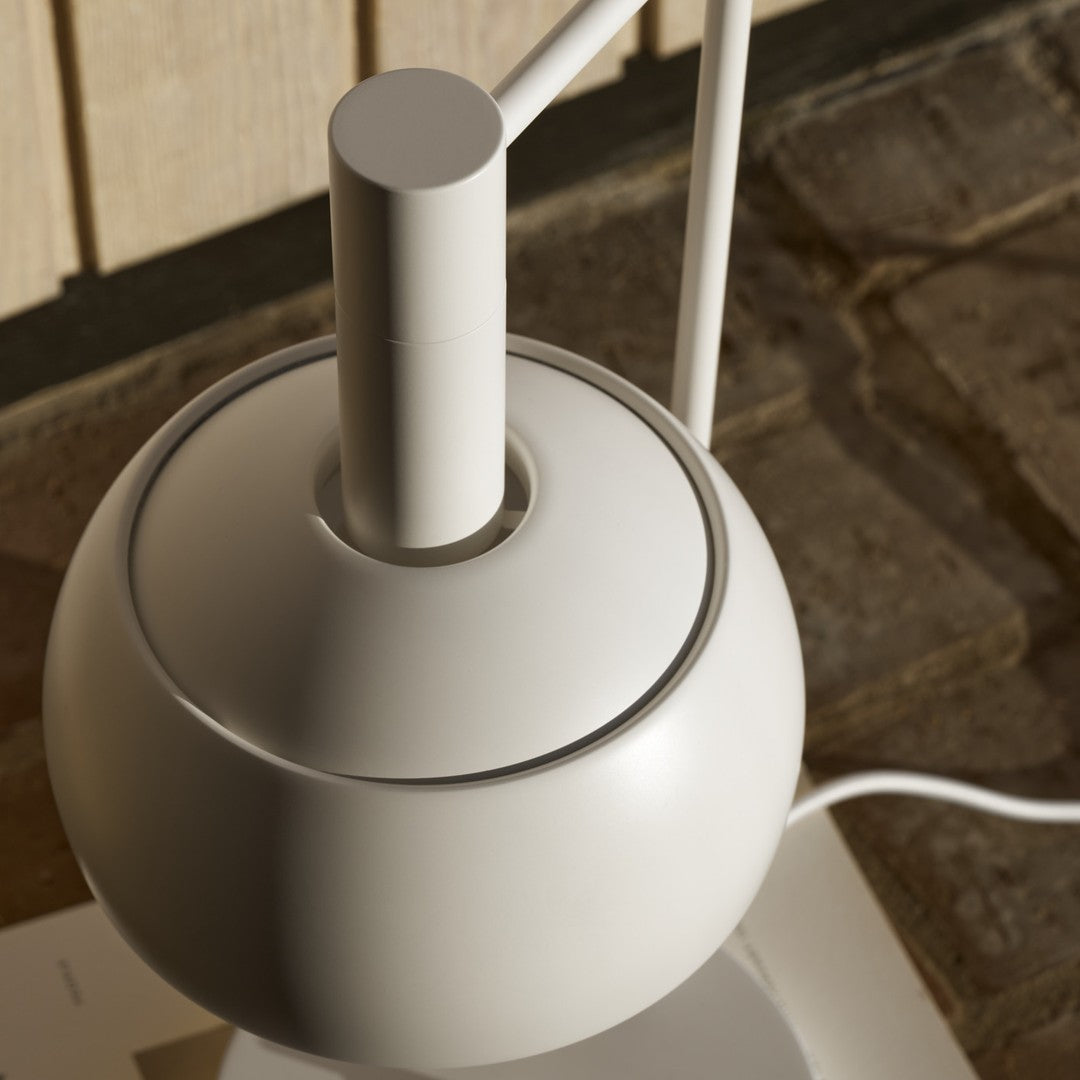 Close-up of a modern white lamp with a metallic base on a wooden surface.