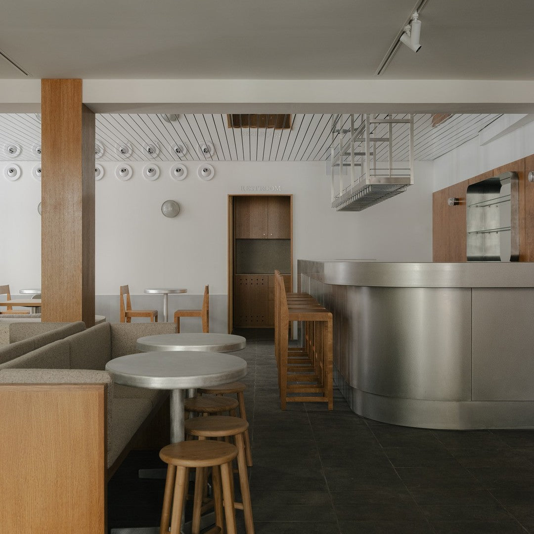 Modern cafe interior featuring neutral tones, wooden accents, and sleek metallic surfaces. Minimalist design aesthetic.