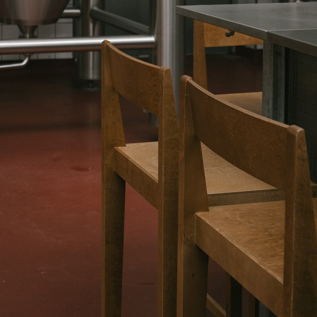 Wooden chairs with a natural finish against a warm red floor, featuring a minimalist design.