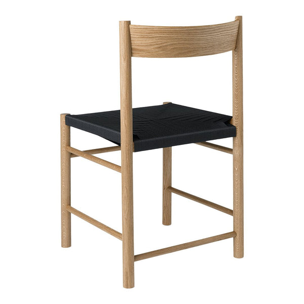 Light wood chair with a simple design featuring a black slatted seat. Sleek, modern, and minimalist aesthetic.