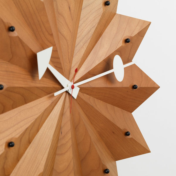 Geometric wooden wall clock with warm wood tones, sharp angles, and contrasting white clock hands for a modern look.