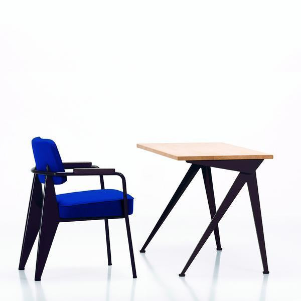 Blue upholstered chair with black metal frame beside a sleek, light wood table with angled black legs.
