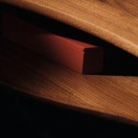 Rustic wooden surface with a subtle sheen, featuring a sleek, deep red box partially hidden in the shadows.