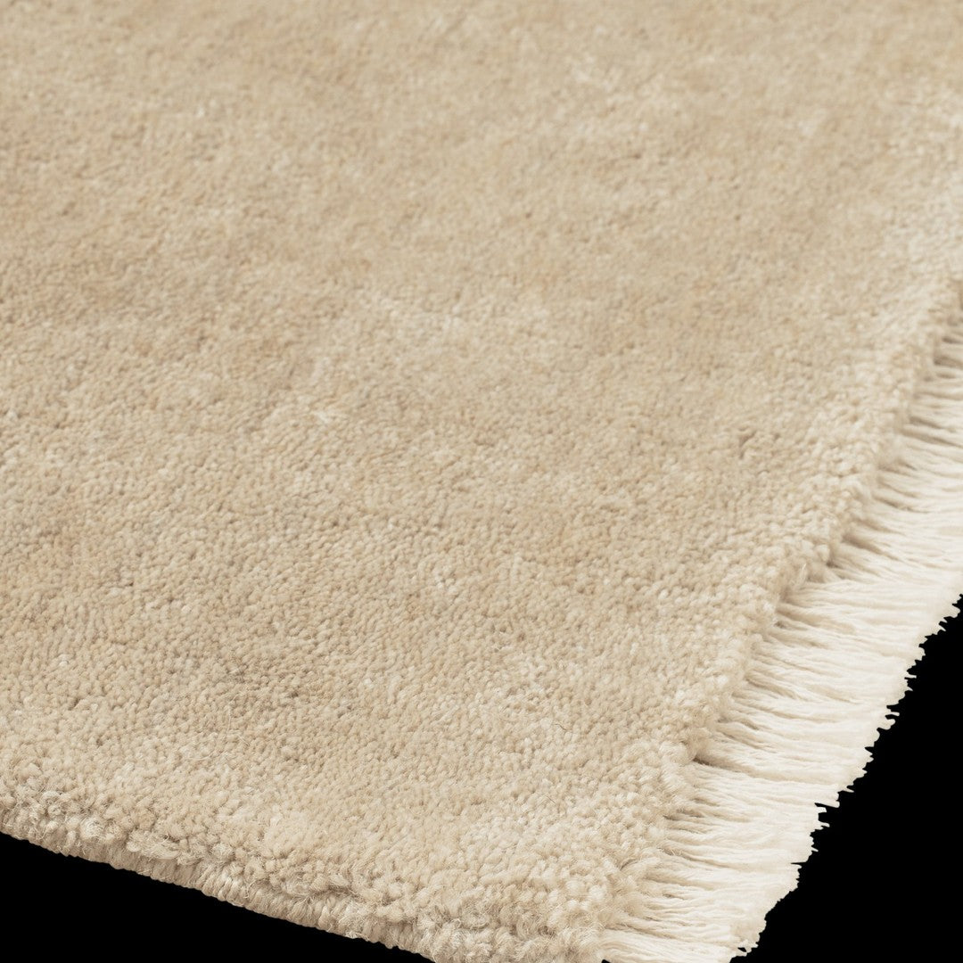Beige plush rug with a soft texture and fringe detail, perfect for adding warmth to any space.