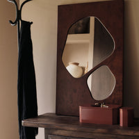 Abstract brown mirror with glossy finish and black textile, complemented by red storage boxes on a wooden table.