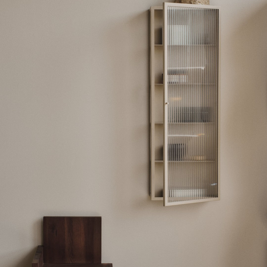 Light cream cabinet with textured glass doors, featuring neutral tones and minimalistic design elements.