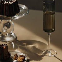 Elegant green ribbed glass and a rich brown bundt cake on a soft beige surface, creating a warm, inviting aesthetic.